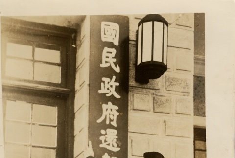 A man putting up a sign on a building (ddr-njpa-6-2)