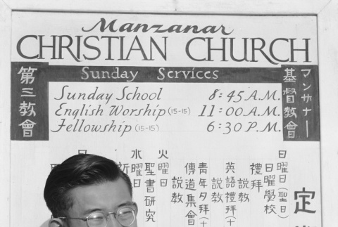 Japanese American in front of Christian church sign (ddr-densho-93-53)