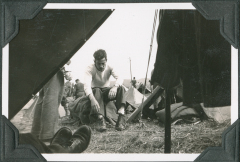 Man sitting on gear outside tent (ddr-ajah-2-261)