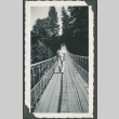 A man walking across a suspension bridge (ddr-densho-328-230)