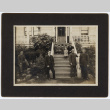 Family standing and sitting on porch steps outside house (ddr-densho-329-595)