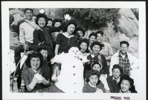 Photograph of a group of people holding snow balls on the side of a mountain with a snowman (ddr-csujad-47-296)