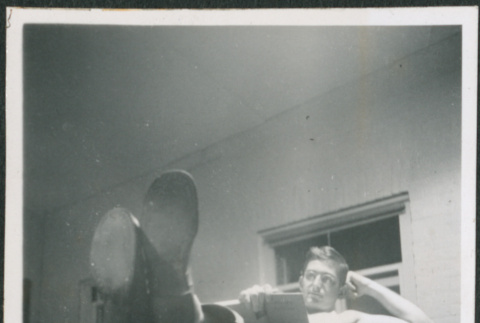 Man laying in bunk, reading (ddr-densho-434-486)