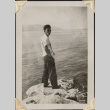 Man standing on rocks by water.  Likely Minoru Muromoto (ddr-densho-466-924)
