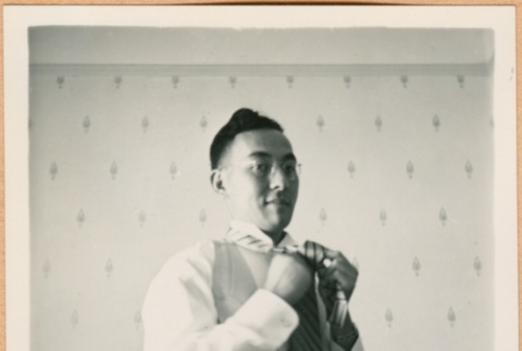 Henri Takahashi adjusting his tie dressing (ddr-densho-410-454)