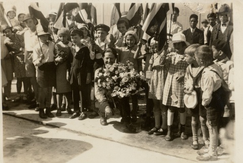 A pilot kneeling with children and holding bouquets (ddr-njpa-1-2219)