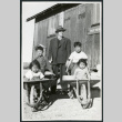 Photograph of B.R. Chamberlain, Ned and Harry Morioka and two other children posing in front of the infirmary at Cow Creek Camp in Death Valley (ddr-csujad-47-138)
