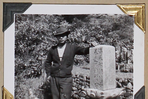 Tokeo Tagami stands next to a gravestone (ddr-densho-404-301)