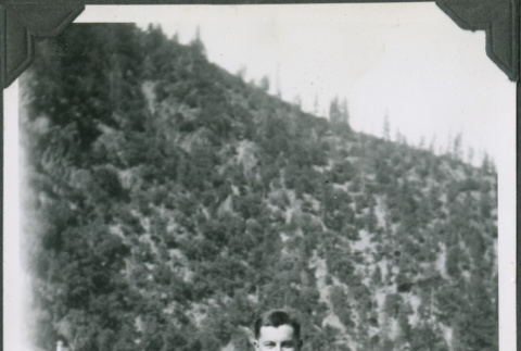Man standing with buildings and hillside in background (ddr-ajah-2-337)
