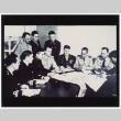 Figures gathered around paper-covered table (ddr-densho-1007-196)