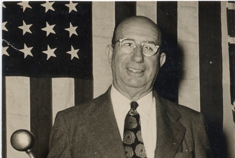 Judge posing in front of a flag, holding a gavel (ddr-njpa-2-796)