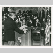 Speaking at podium with flag (ddr-densho-1007-214)