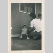 Toddler girl with two women outside barracks (ddr-densho-329-1344)