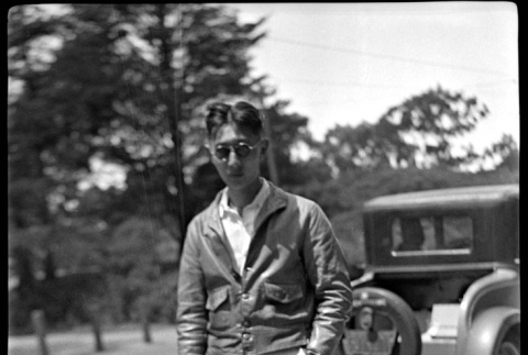 Man in leather jacket and sunglasses standing by car (ddr-densho-426-1832)