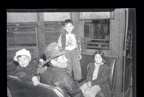 Adult male and three children from Terminal Island sit on benches in a train car (ddr-csujad-54-4)