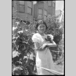 Girl holding kitten standing by hollyhocks (ddr-densho-426-2017)