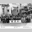 Group photo outside building, holding banner in Japanese (ddr-ajah-3-185)