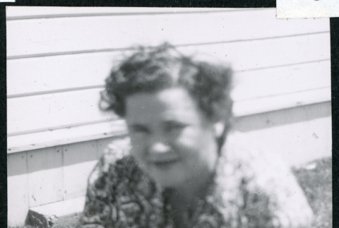 Photograph of Lucy Adams sitting on the grass in front of staff housing at Manzanar (ddr-csujad-47-170)