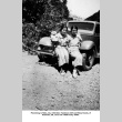 Two women sitting on car fender (ddr-ajah-6-108)