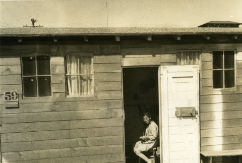Woman sitting in the doorway of her Assembly Center barracks (ddr-densho-22-447)