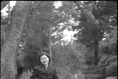 Tomoye (Nozawa) Takahashi standing by metal fence (ddr-densho-426-2179)