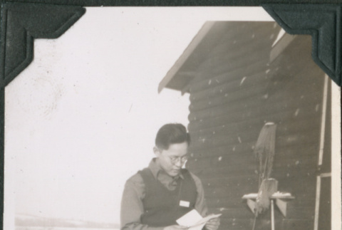 Man reading outside camp building in snow (ddr-ajah-2-464)