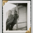 Two men sitting on railing, icicles on roof behind (ddr-densho-434-296)