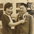 Young woman placing a lei on a man (ddr-njpa-4-95)