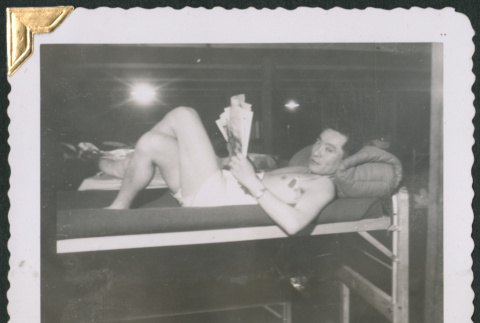 Man laying on bunk reading (ddr-densho-434-277)