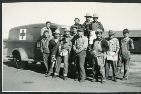 Photograph of a construction crew standing in front of a U.S. Army ambulance at Manzanar (ddr-csujad-47-184)