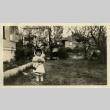 Nisei girl with doll in backyard of house (ddr-densho-182-154)