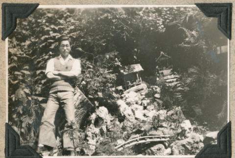 Isamu Ito in front of huts in forest (ddr-densho-383-182)
