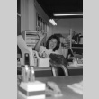 Woman waving at desk (ddr-densho-1007-561)