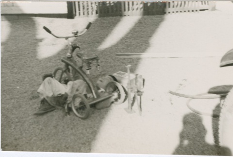 A boy laying under a tricycle (ddr-densho-338-262)