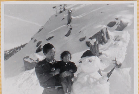 Hardy Shiomi holding Susan Shiomi next to snowman (ddr-densho-522-239)
