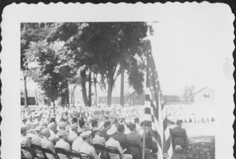 Crowd of men seated, flag in foreground (ddr-densho-434-399)
