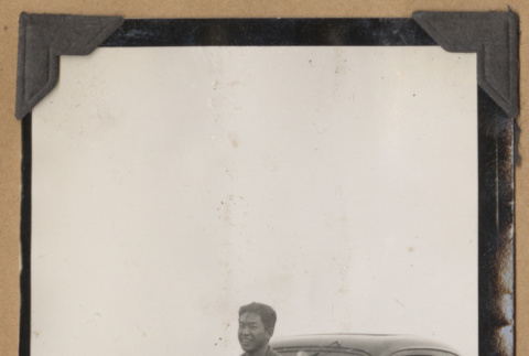 Man seated on a car fender (ddr-densho-542-141)