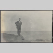 Man standing on rock by shore (ddr-densho-355-592)