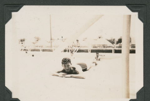 Man laying down by swimming pool (ddr-densho-545-42)