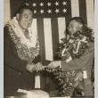 Two men wearing leis in front of a flag (ddr-njpa-2-303)