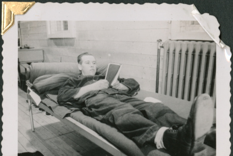 Man laying in bunk, reading (ddr-densho-434-185)