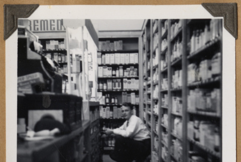 Man squatting behind a counter (ddr-densho-542-102)