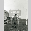 Soldier in front of a road sign for Dachau (ddr-densho-22-106)