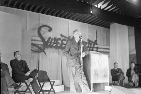 Harry L. Stafford speaking on a stage before a Sweetheart dance (ddr-fom-1-432)