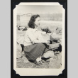 Woman seated beside a wood pile (ddr-densho-542-716)