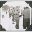 Group standing in snow, man in center looking at camera (ddr-ajah-2-453)