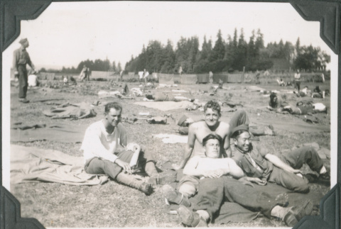 Four men sitting in field with gear and tents (ddr-ajah-2-243)