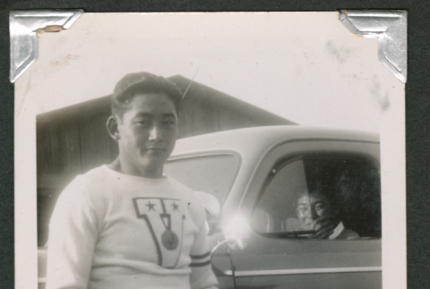 Man leaning on car with someone inside (ddr-densho-550-142)