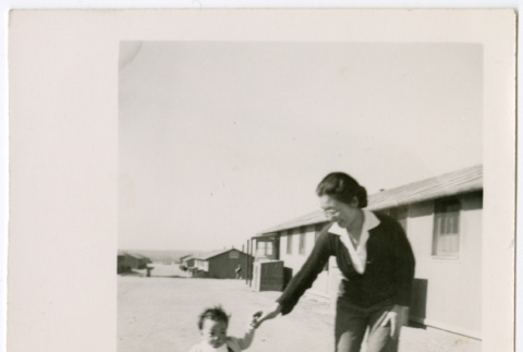 Sally Domoto walking with toddler outside barracks (ddr-densho-329-1339)