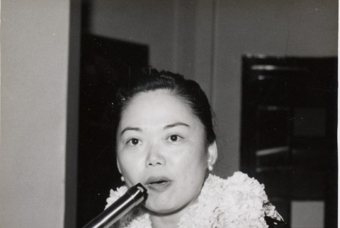 Woman wearing leis speaking at a podium (ddr-njpa-2-710)
